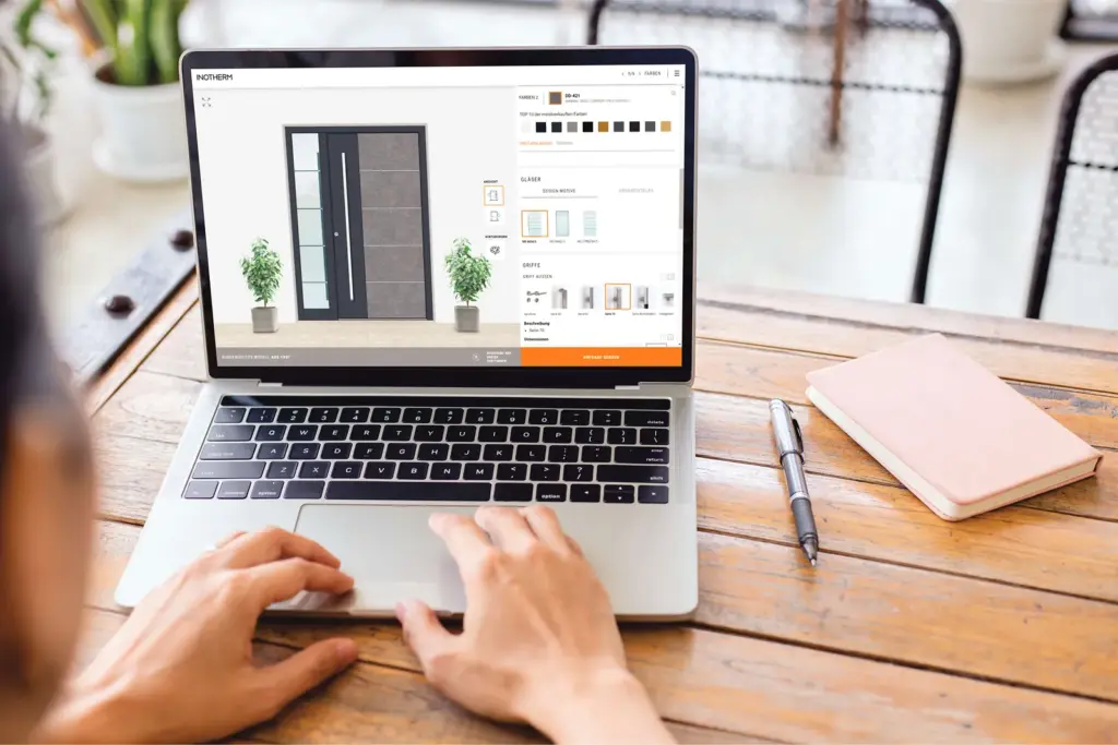 Hände an einem Laptop, auf dem im Online-Konfigurator eine graue Haustür mit Seitenteil gestaltet wird – Bild: Inotherm